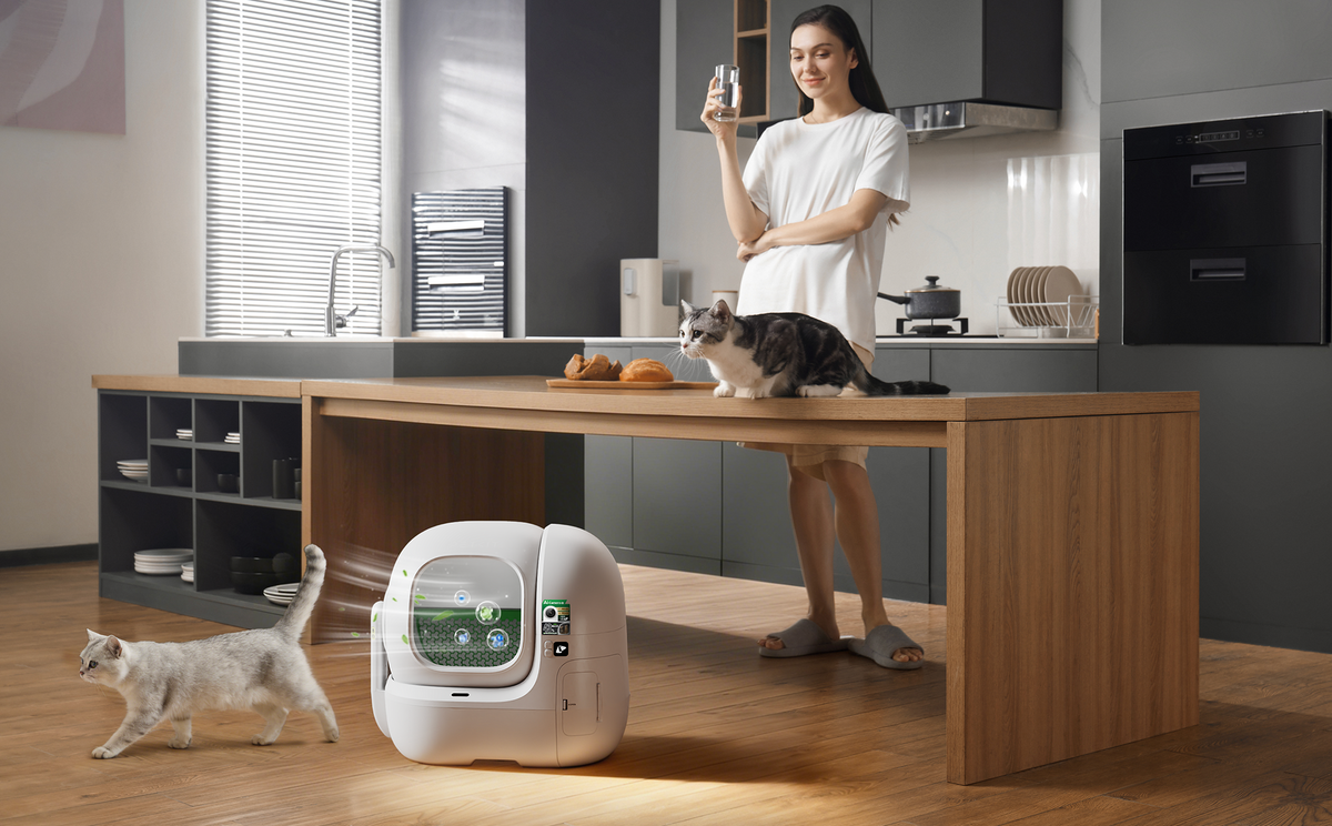 PETKIT automatic self-cleaning litter box with advanced odor control design, in a modern kitchen with two cats and a pet owner, demonstrating a clean, fresh home for multi-cat households.